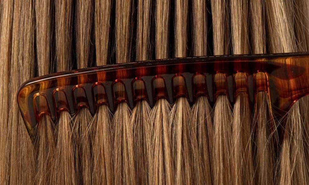 Close-up of a comb gliding through healthy, shiny hair